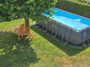 a wooden bench sitting under a tree next to a swimming pool at Charly`s Place in Rain