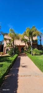a walkway with palm trees in front of a building at Belle villa avec piscine privée in Ala el Ma