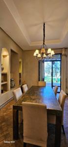 a dining room table with chairs and a chandelier at Belle villa avec piscine privée in Ala el Ma