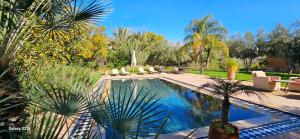 a swimming pool in a yard with chairs and trees at Belle villa avec piscine privée in Ala el Ma