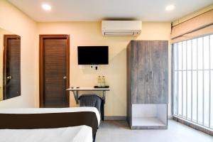 a room with two beds and a desk and a tv at Hotel O Premium 12th Night in kolkata +22 photos