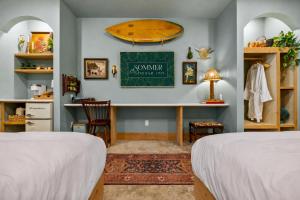 a bedroom with two beds and a desk with a surfboard on the wall at Sommer House Inn-Aloha Room in Jasper