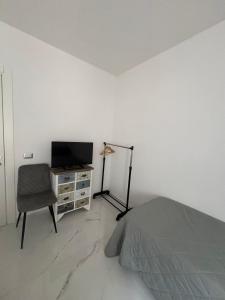 a bedroom with a bed and a tv and a chair at BEB LA Perla in Sammichele di Bari