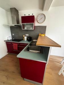 a kitchen with red cabinets and a clock on the wall at Au Morvan Voyageur in Asquins