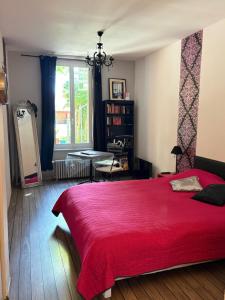 a bedroom with a red bed and a window at La Cathare in Lézignan-Corbières