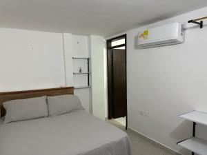 a white bedroom with a bed and a air conditioner at Edificio Don Ramon in Valledupar