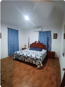 a bedroom with a bed with blue curtains and wooden floors at Casa chalet in Chiquimula +12 photos