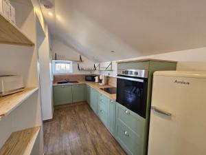 a kitchen with green cabinets and a white refrigerator at Cottage de la Maye in Rue