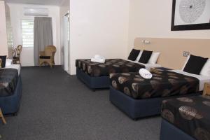 a hotel room with two beds and a television at Jackaroo Motel in Mareeba