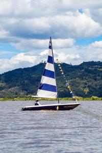 a man on a sail boat on the water at La Gruta Glamping in Fúquene