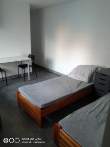a room with two beds and a desk and a table at Noclegi Tuszyn S in Tuszyn