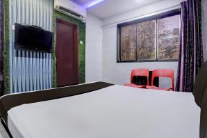 a bedroom with a bed and two red chairs at Hotel O Jayesh Inn in Kolshet