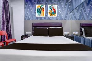 a bedroom with a bed and three paintings on the wall at Hotel O Jayesh Inn in Kolshet