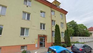 a yellow building with cars parked in front of it at 2 bedroom apartment, near Xbionic in Šamorín
