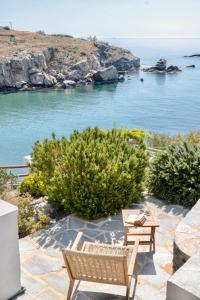 two benches sitting on a patio near the water at Demetra Waterfront House-Authentic Syros, by Elefthia Syros in Megas Gialos - Nites