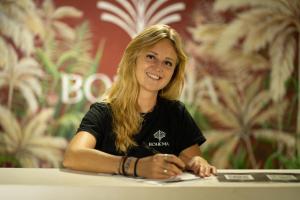 a woman sitting at a table smiles at the camera at Bohemia Boutique Hostel in Cali