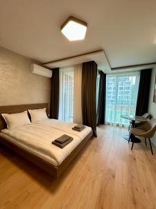 a bedroom with a large bed and a desk and windows at Eleve Residences - Sand Studio in Sofia