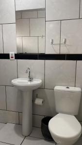 a white bathroom with a toilet and a sink at HOTEL REAL in Marechal Cândido Rondon