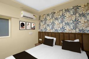 a bedroom with a bed with white sheets and black pillows at Super Hotel O RS PALACE in Jhānsi