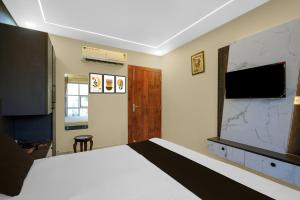 a bedroom with a large bed and a flat screen tv at Super Hotel O RS PALACE in Jhānsi