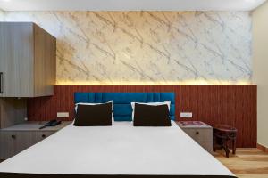 a bedroom with a large white bed with a blue headboard at Super Hotel O RS PALACE in Jhānsi