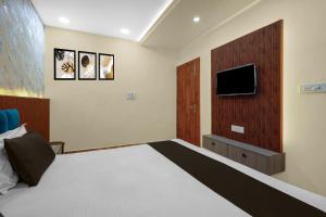a bedroom with a bed and a tv on the wall at Super Hotel O RS PALACE in Jhānsi