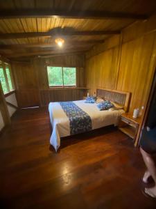 a bedroom with a bed in a wooden room at Hotel El Abrazo del Arbol in Mindo