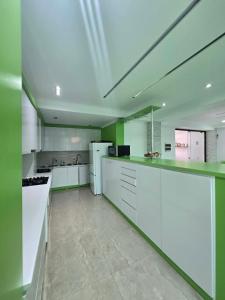 a large kitchen with white appliances and green walls at Green House in Ureki