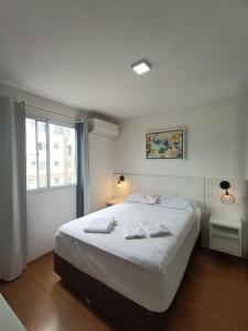 a bedroom with a large white bed and a window at Acomodações Azaleias by Rental in Palhoça