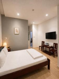 a bedroom with a bed and a desk and a television at Salyna Motel in Danang