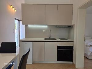a kitchen with white cabinets and a sink at APARTMENTS BRUNO 3 - two-room penthouse apartment - wonderful view of the sea - the best location, first row to the beach - 10 minutes from Supetar ferry port - free secured parking - facilities nearby in Sutivan