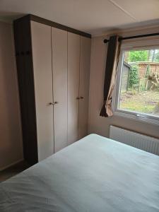ein Schlafzimmer mit einem Bett und einem Fenster in der Unterkunft Roosje in Hoenderloo