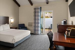 a hotel room with a bed and a desk and a window at Cannery Row Inn in Monterey