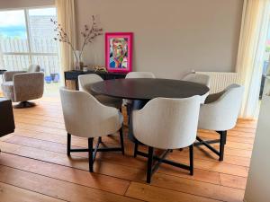 a dining room with a black table and white chairs at Villa Water en Meer in Terherne