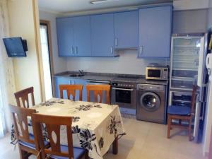a kitchen with blue cabinets and a table and chairs at Duplex Playa Rapadoira con piscina in Foz