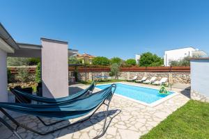 a patio with a hammock and a swimming pool at Holiday Home Casa Vida in Rakalj
