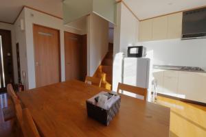 a kitchen with a wooden table and a refrigerator at Cottage Pastorale in Fujikawaguchiko