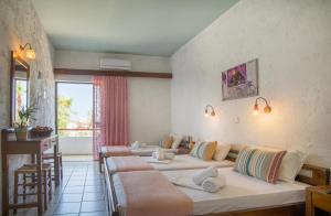 a hotel room with three beds and a table at Violetta Hotel in Amoudara Herakliou +165 photos