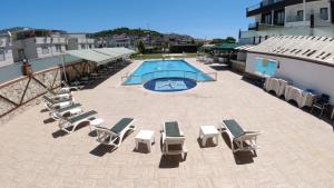 a group of lounge chairs and a swimming pool on a building at Alptekin Otel in Ürkmez