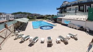a patio with chairs and a swimming pool on a building at Alptekin Otel in Ürkmez