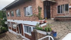 a brick house with two windows and potted plants at S-and Kasa Guest House in Pietermaritzburg