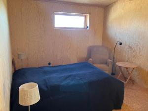 a bedroom with a bed and a chair and a window at The forest in Sjöbo