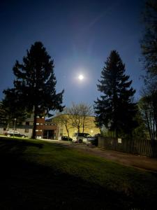 a moon over a parking lot with trees and a building at Ferienwohnung Molly inclusive Hallenbad, Sauna, Fitnessstudio und Aussenpool in Sankt Englmar