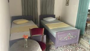 two twin beds in a room with a table and a table sidx sidx at Beit Emna3 in Kairouan