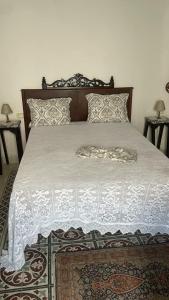 a bed with a white comforter and pillows on it at Beit Emna3 in Kairouan