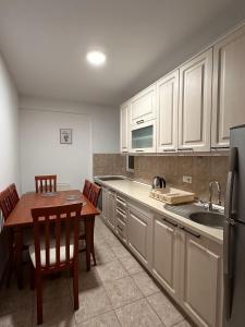 a kitchen with white cabinets and a table and a sink at Boulevard Mitrovica in Mitrovica