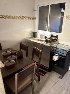 a kitchen with a stove and a table with chairs at Casa próximo da Havan, UFMS e ArenaMix com Garagem in Três Lagoas