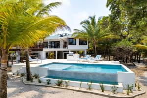 a house with a swimming pool and palm trees at Picture-Perfect 2-Bedroom Oceanfront Home w Pool in Placencia