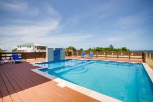 a swimming pool on top of a deck with chairs at Elegant Beachfront Villa Pool & Beach Family Fun in Maya Beach