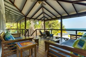a porch with benches and tables and a view of the ocean at Spacious Beachfront Family Home w Caribbean Views in Maya Beach